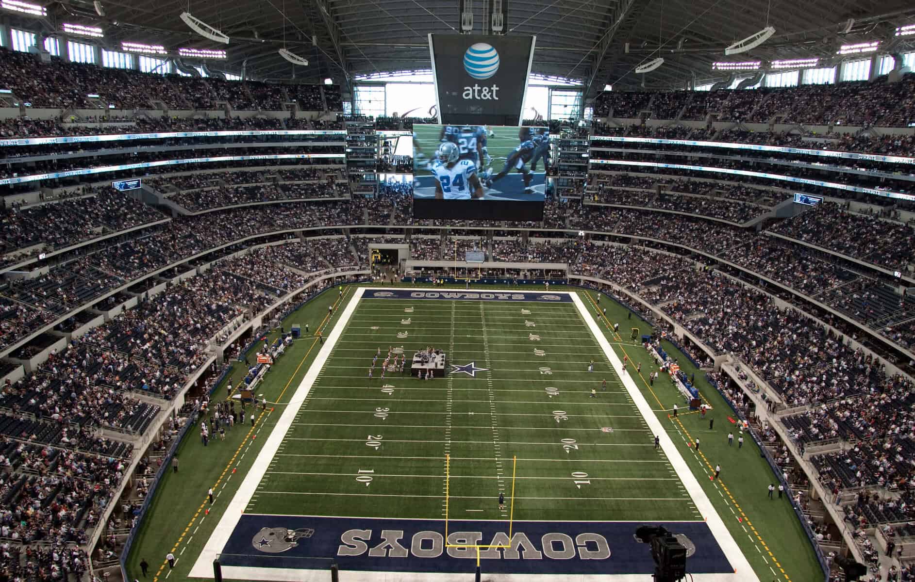 Inside AT&T Stadium during a Cowboys game with packed crowd and large screen.