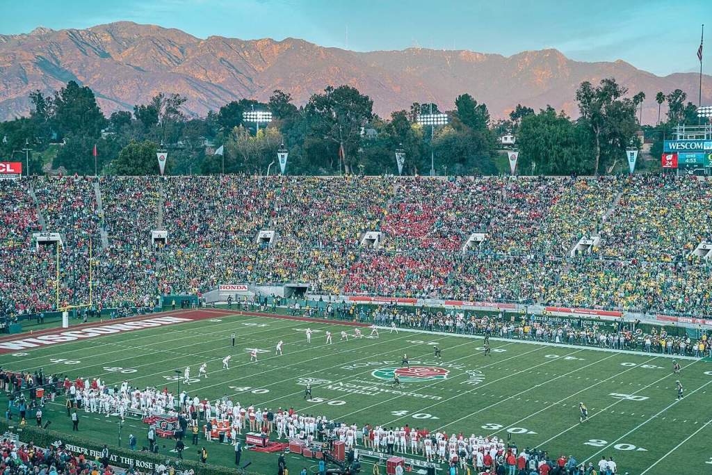 A large stadium with a football field and mountains in the background. photo credit: wikipedia