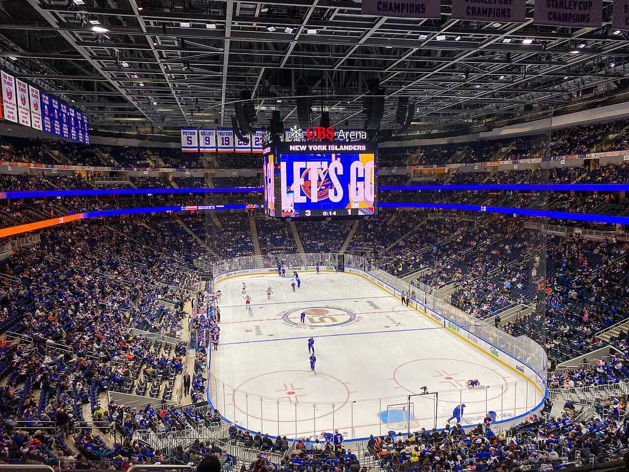 Inside UBS Arena during a New York Islanders game with fans and players on ice.